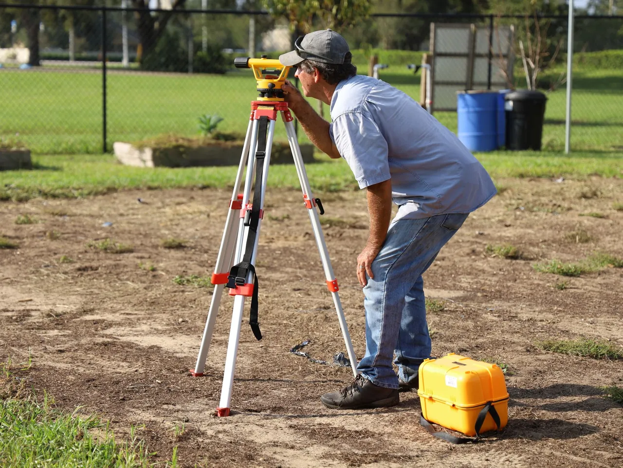 A land surveyor sighting through a level on a tripod in an open lot