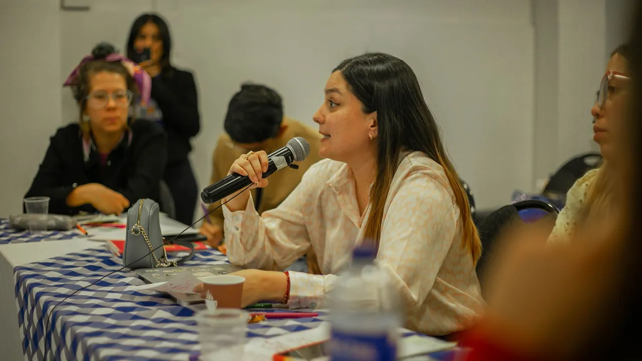 A woman speaking into a microphone during a community meeting